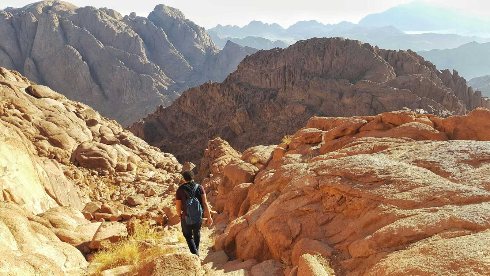 Hiker walking through the rugged mountains of South Sinai, capturing the vast landscape.