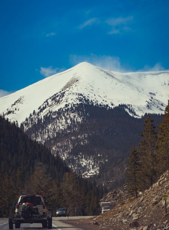 Cars travel on a highway through stunning snow-capped mountains, perfect for adventure enthusiasts.